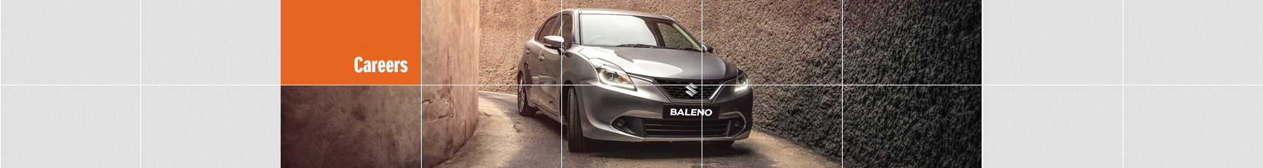 Suzuki Baleno sedan in premium silver metallic paint in a narrow alley.