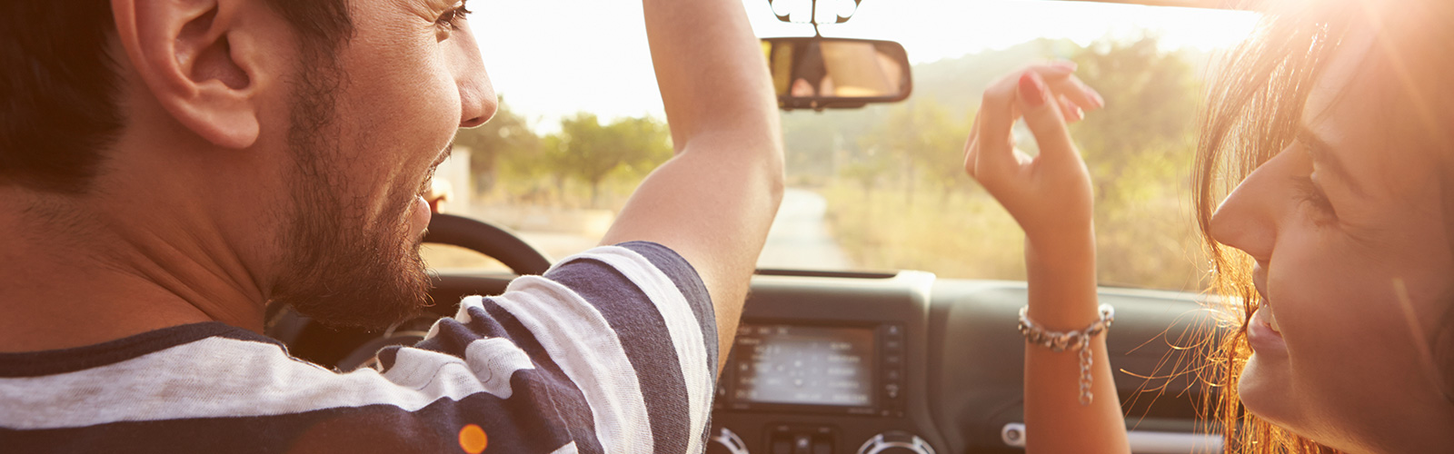 A happy couple dancing in the front seats of their car.